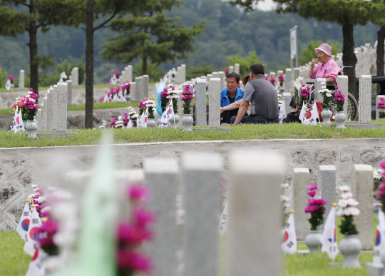 제63회 현충일을 이틀 앞둔 4일 오후 서울 동작구 국립서울현충원을 찾은 시민들이 묘비 앞에서 이야기를 하고 있다.